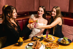A group of friends Enjoying their meal at Soluna Toronto Restaurant looking happy while having a toast